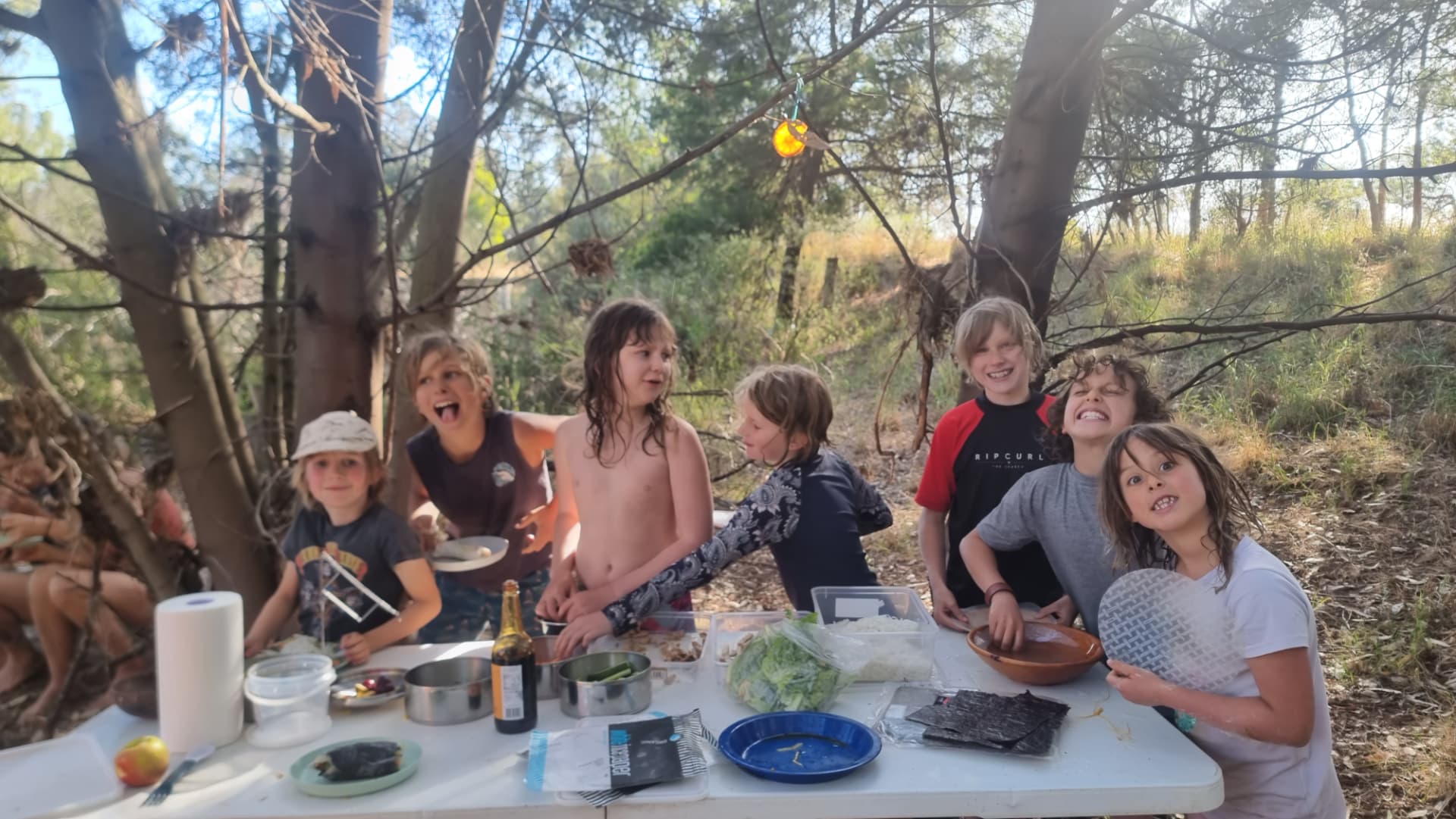 Children sharing food around a camp table in the bush