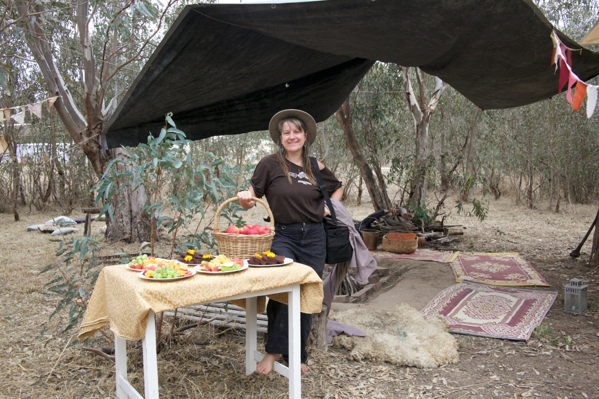 Nectar with a basket of apples beside a shared fruit table under a tarp