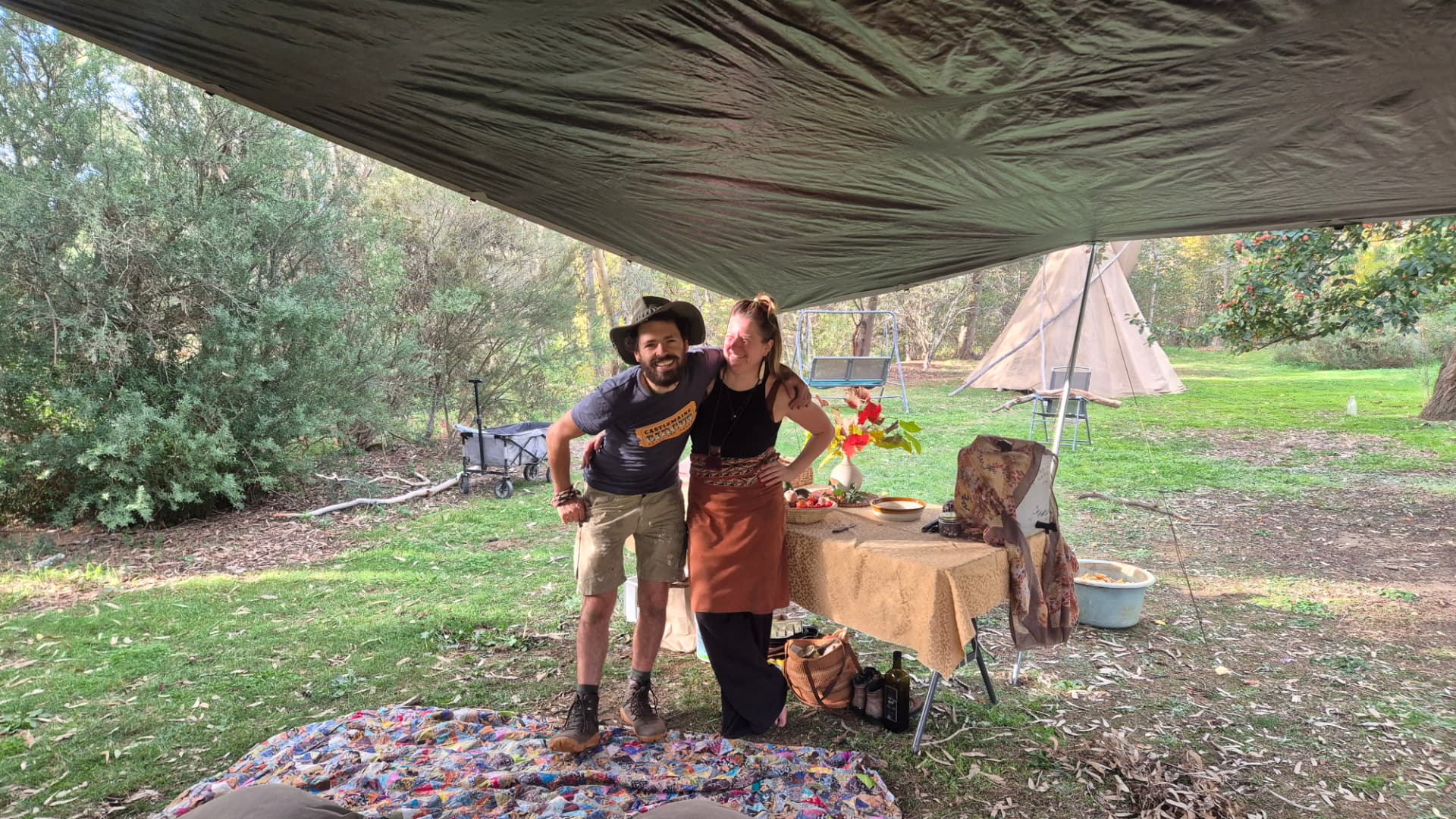Two mentors under the tarp beside the tea and food table