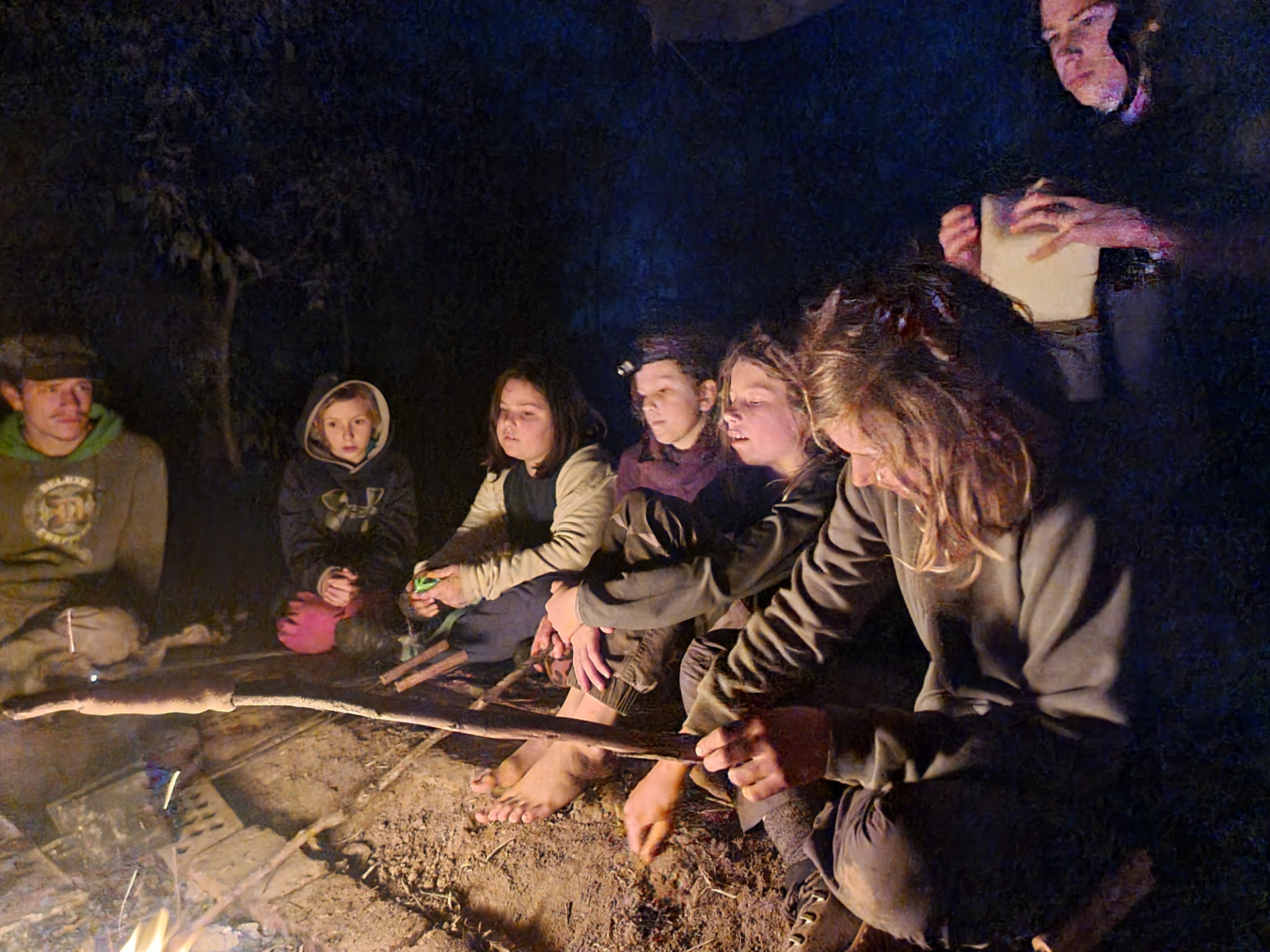 Kids and mentors sitting together around the fire at night