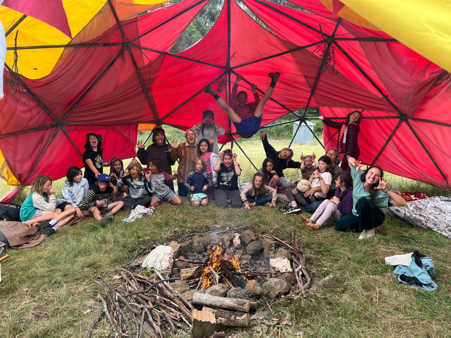 The whole crew being silly under the red dome beside the fire