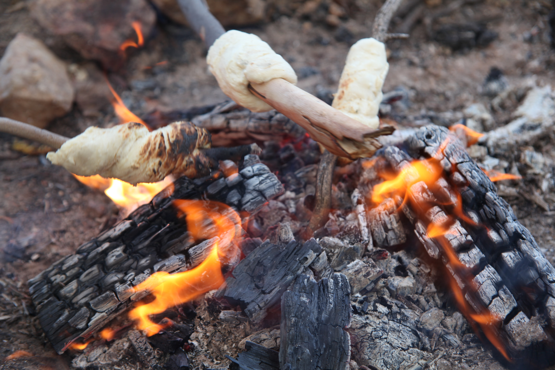 Damper bread cooking on sticks over a campfire