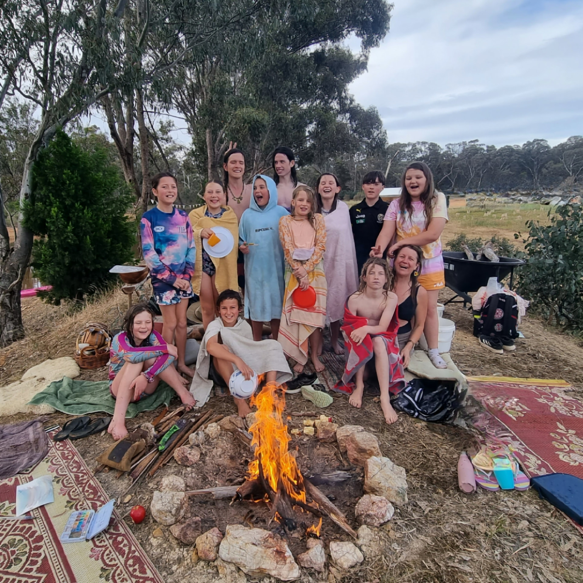 Kids and mentors gathered around a campfire at a Punk Caterpillar camp