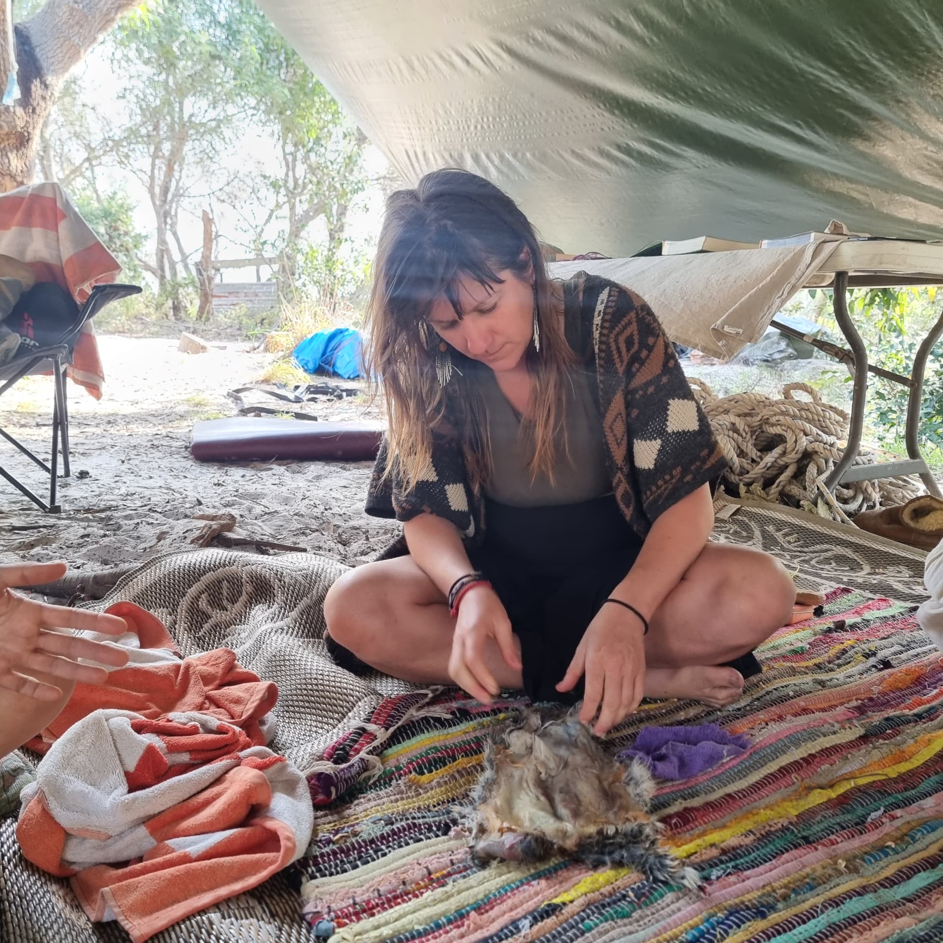 Nectar working on a natural craft under a tarp shelter