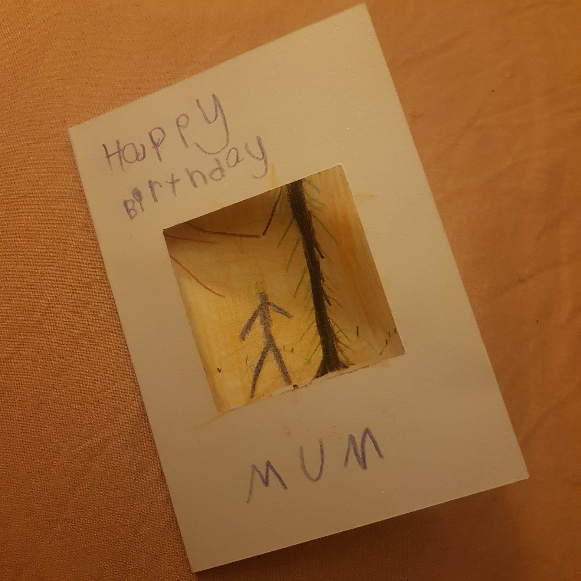 A handmade birthday card that reads Happy Birthday Mum, with a small window cut into the front