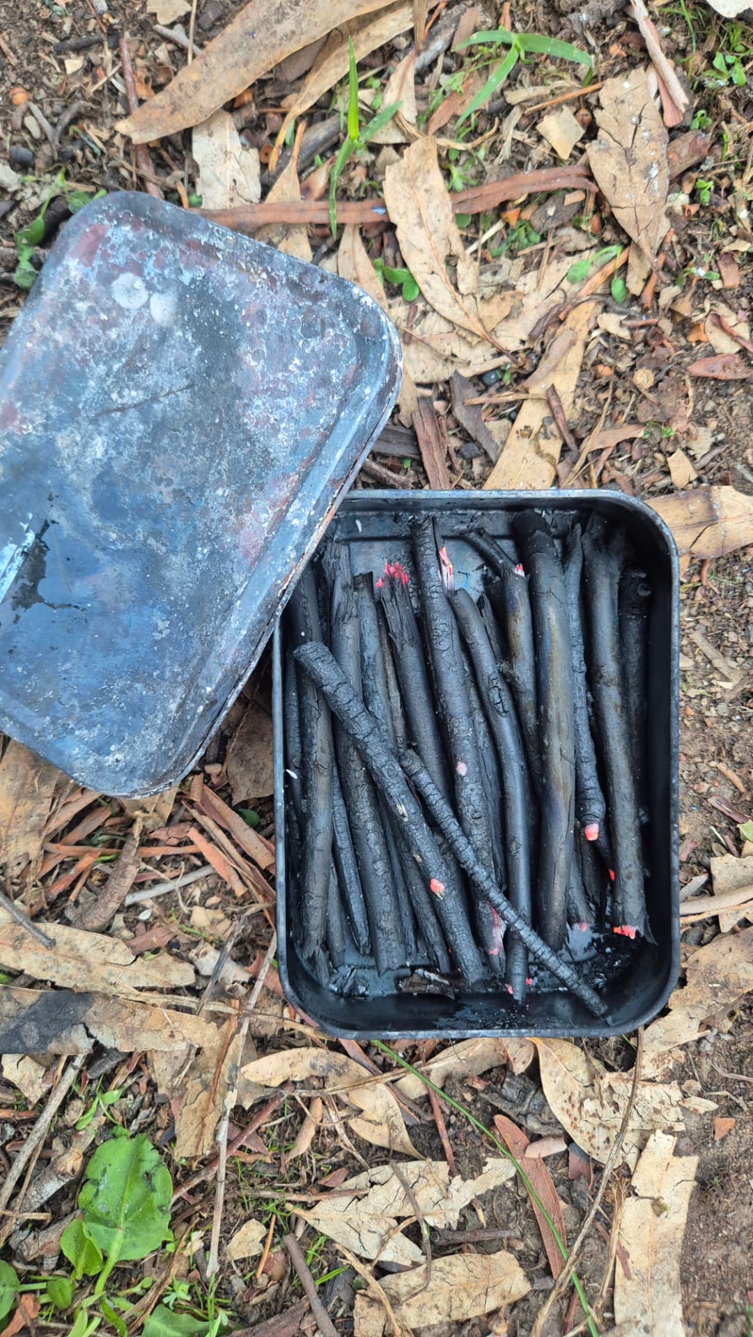 A tin of charcoal drawing sticks made in the fire