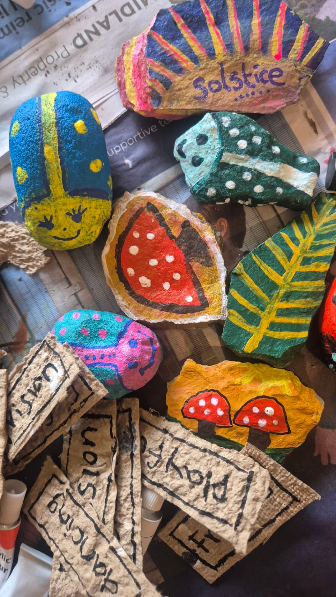 Painted solstice stones drying on newspaper
