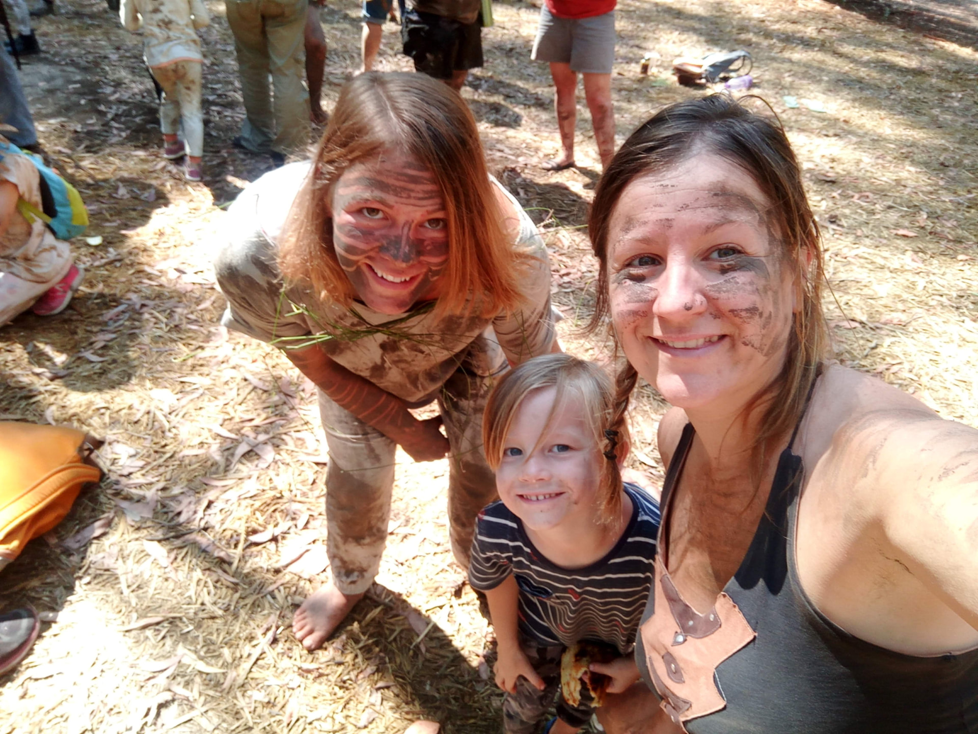 Nectar and friends smiling with camouflaged mud face paint in the bush