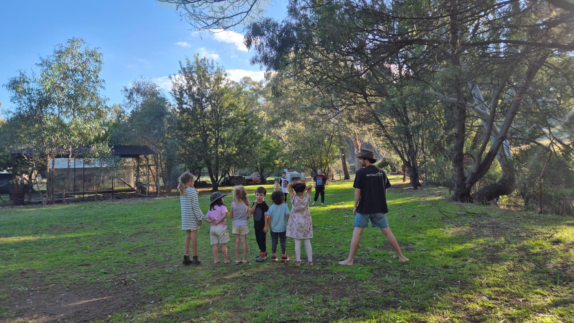 Kids and a mentor playing a game on the grass in the afternoon sun