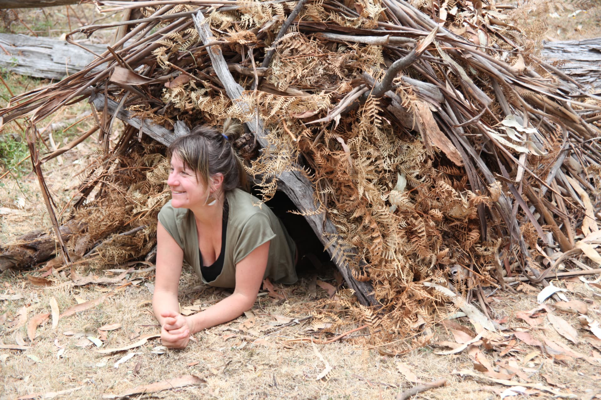 Nectar smiling inside a shelter built from ferns and branches