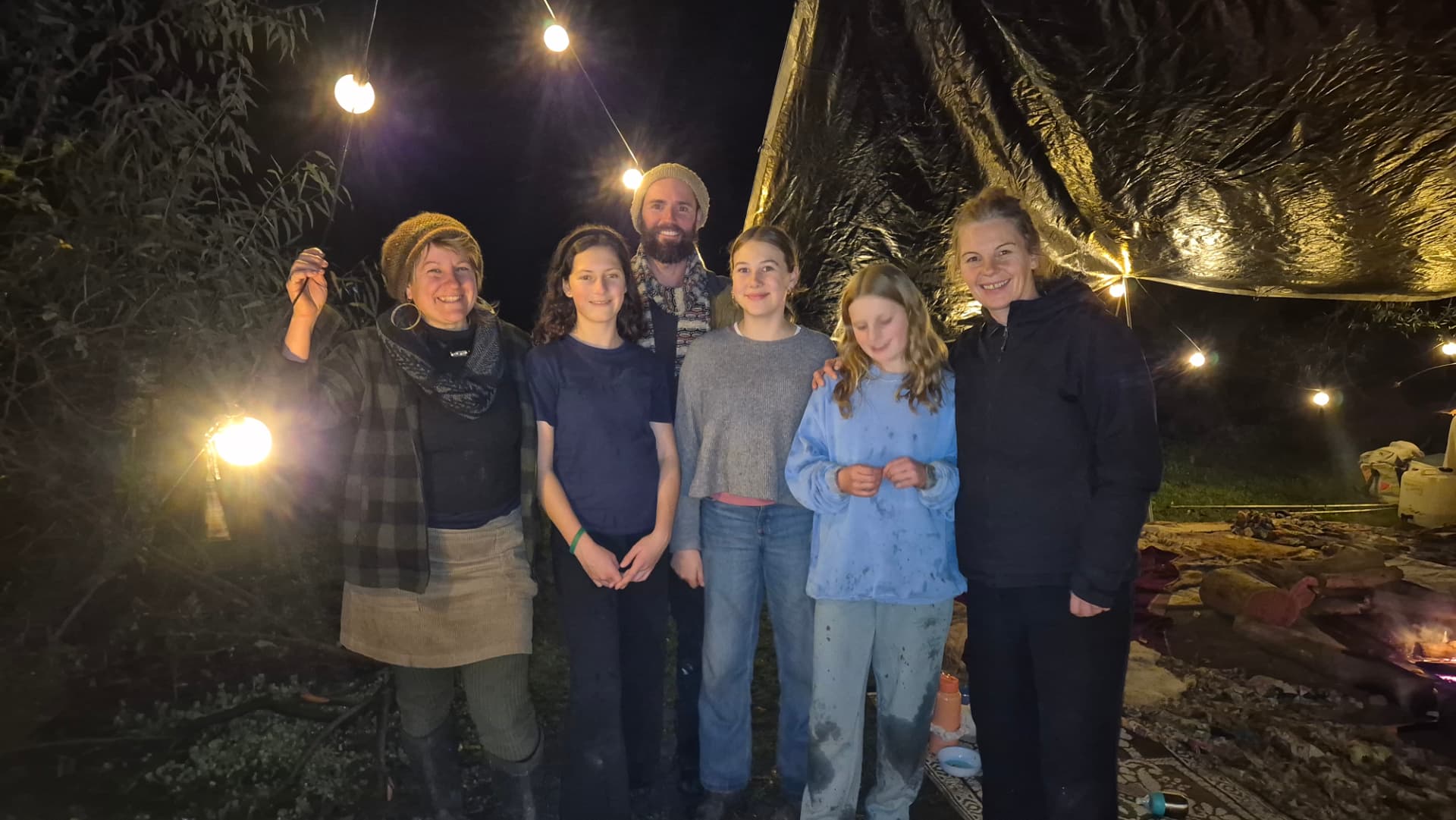 Mentors and kids under festoon lights at the solstice gathering
