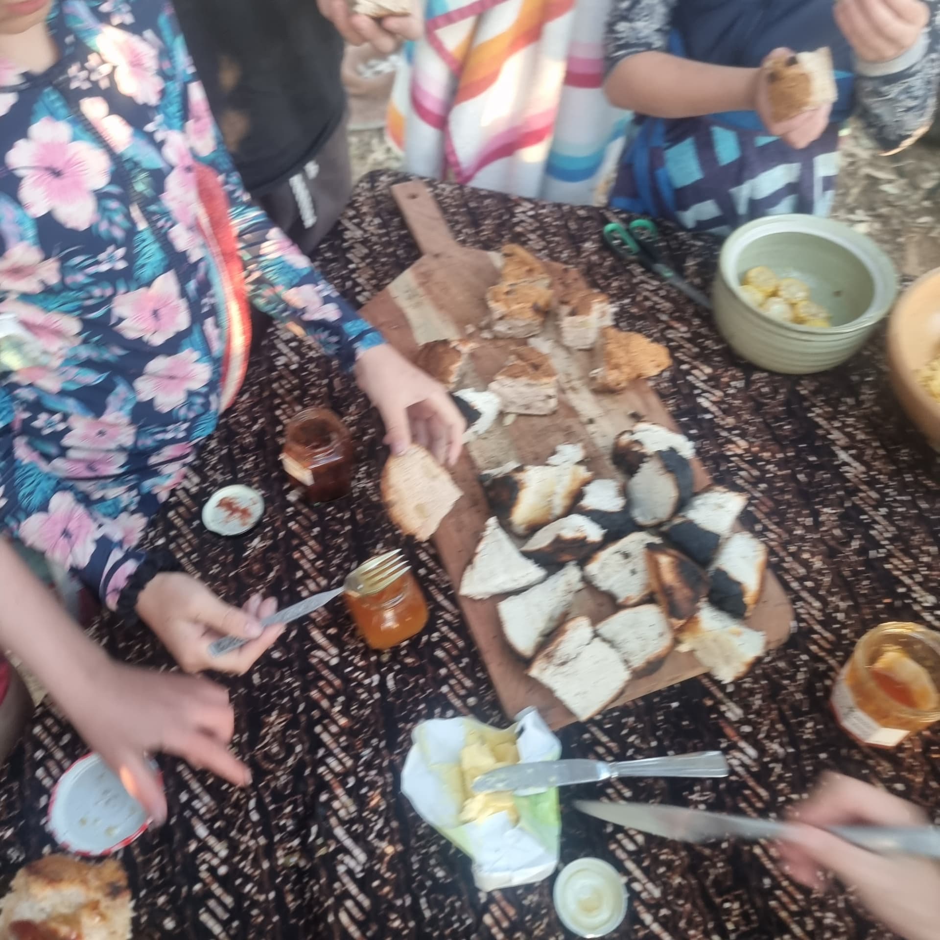 Freshly baked damper with jam on a sharing board at camp