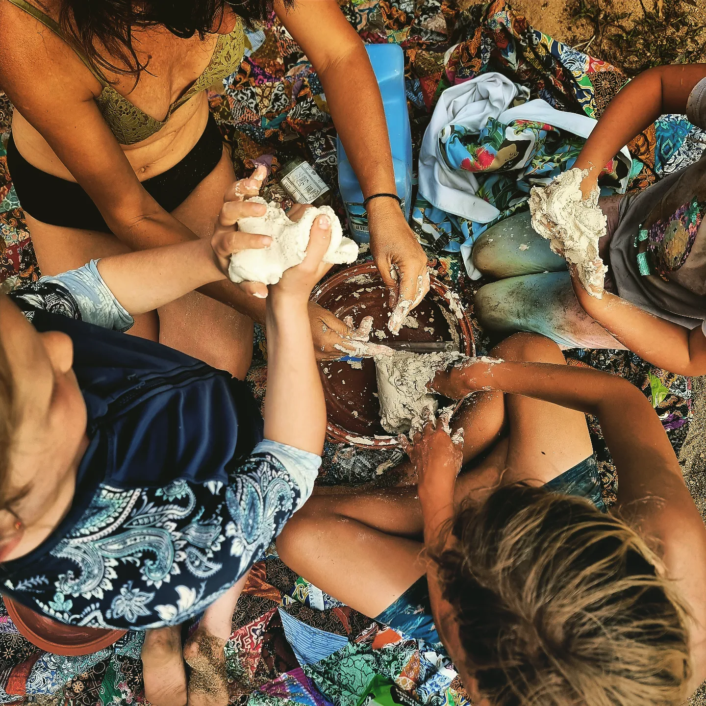 Kids and parents shaping clay together on a patterned rug