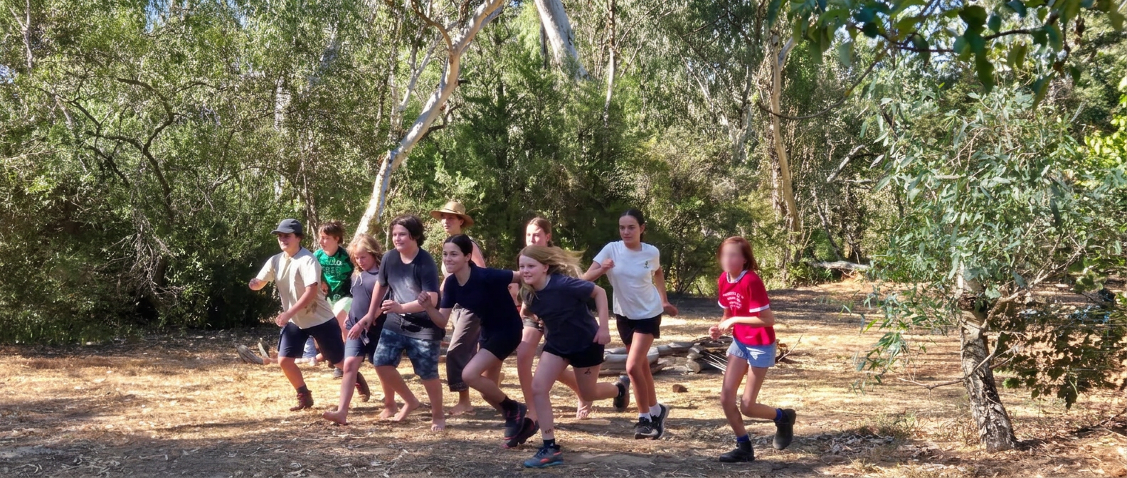 Young people running together through a bush clearing